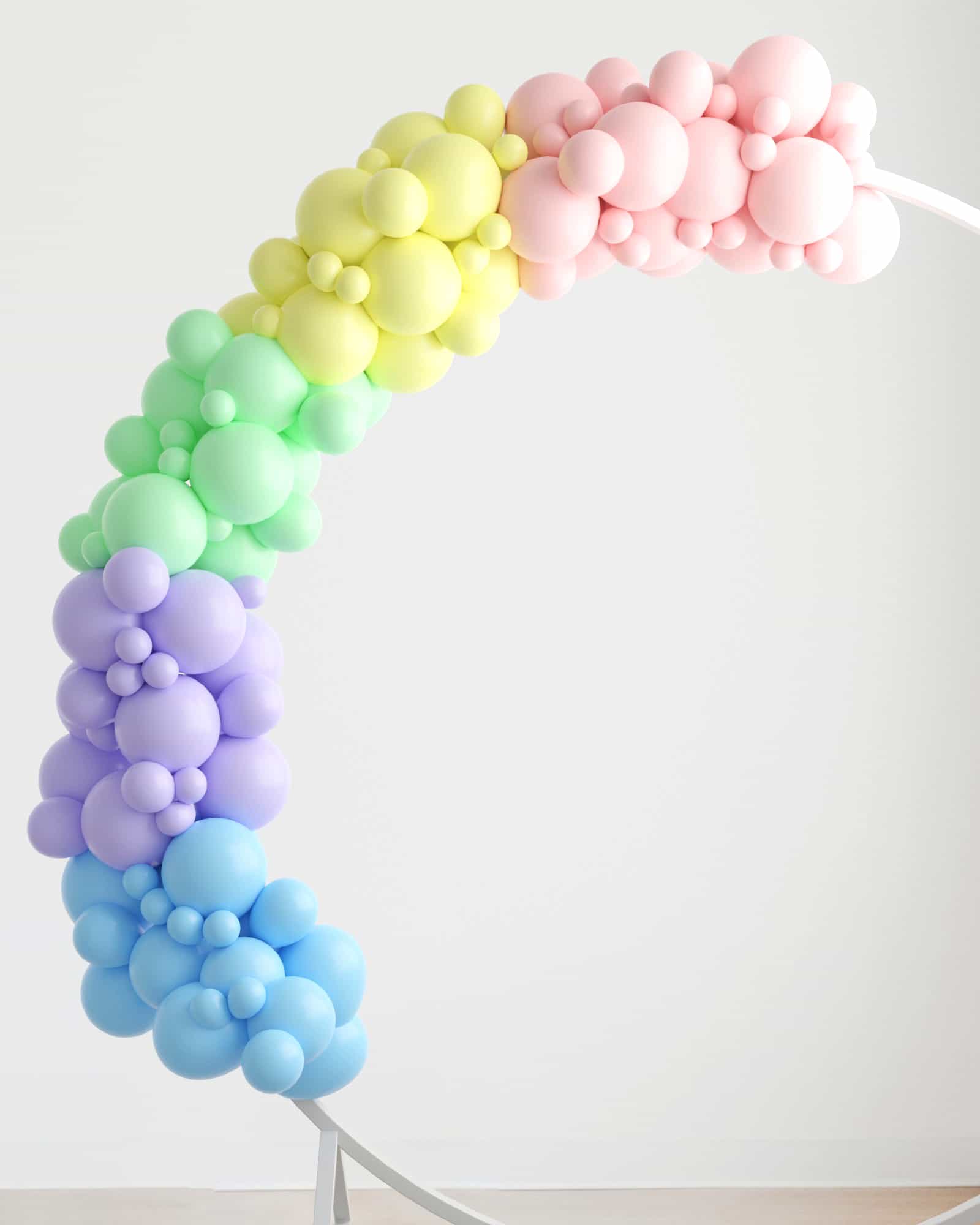 Colorful balloon garland in pastel shades of pink, yellow, green, and blue, curved gracefully against a light background.