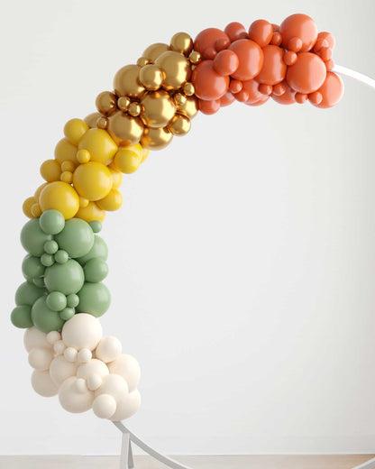 Colorful balloon garland in shades of orange, gold, yellow, green, and white, creating a festive arch shape.