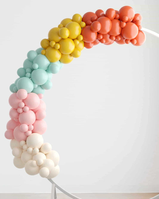 Colorful balloon garland featuring pastel shades of pink, blue, yellow, and orange arranged in a whimsical arch.