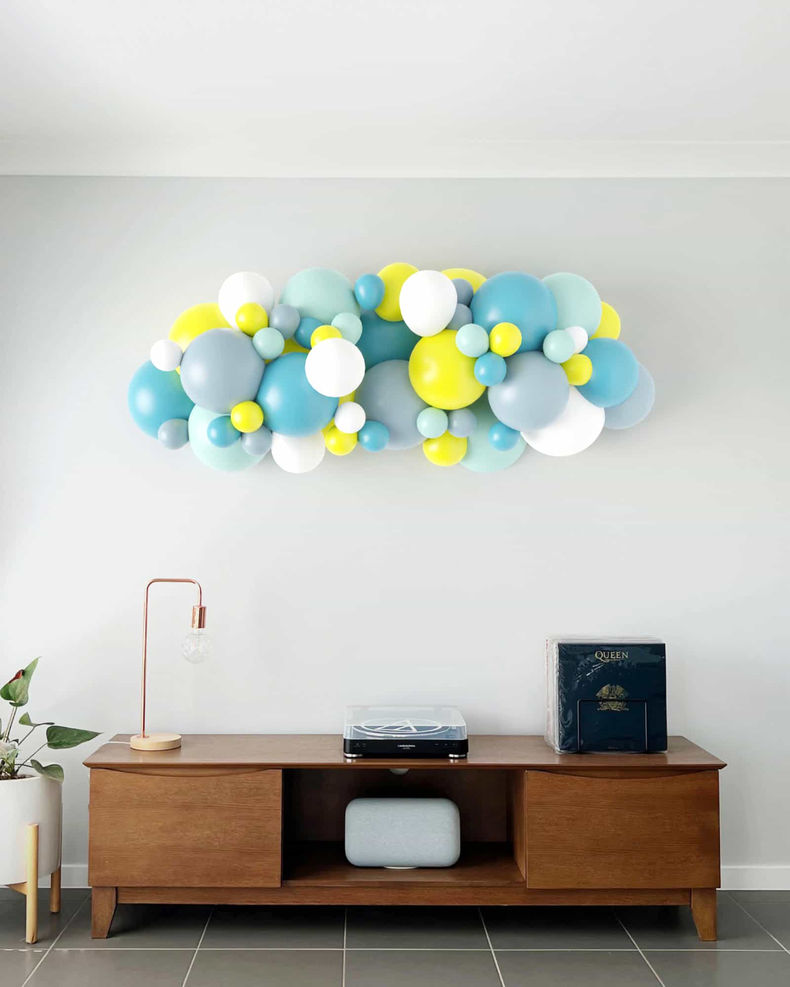 A colorful garland of balloons in blue, yellow, and white, adding a festive touch to a modern living space.