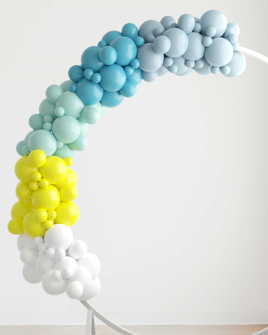 Colorful balloon garland in shades of blue, yellow, and white, arching gracefully against a light background.