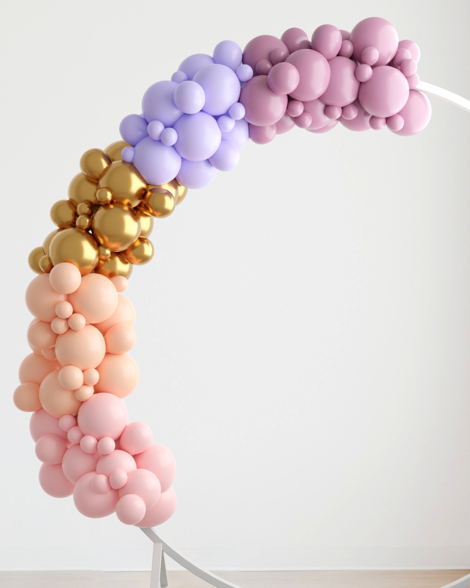 Colorful balloon garland in shades of pink, lavender, gold, and peach, gracefully arching against a light backdrop.
