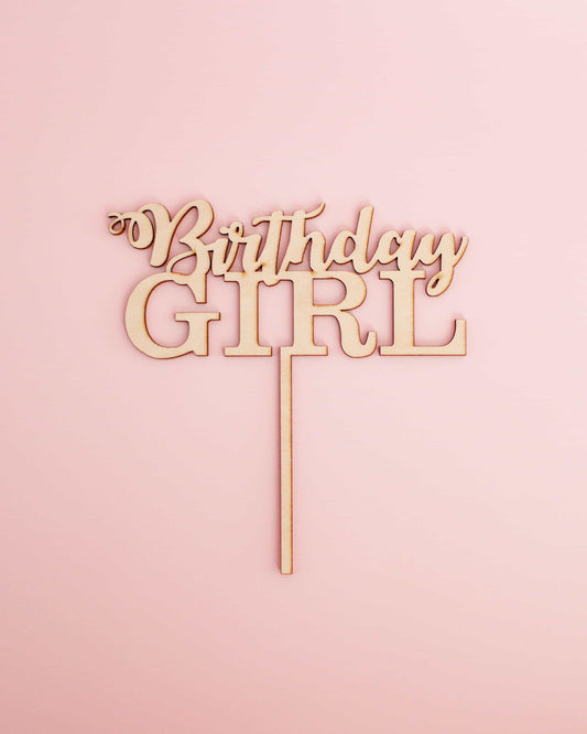 Wooden cake topper featuring the phrase "Birthday Girl" in an elegant font against a soft pink background.