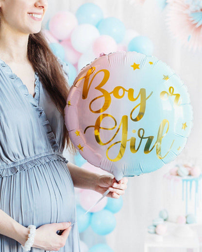 A pregnant woman holds a pastel balloon that reads "Boy or Girl," surrounded by colorful balloons and festive decor.