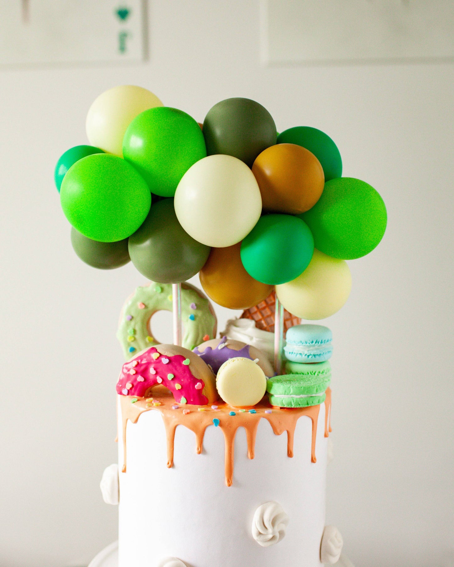 Colorful balloons atop a cake adorned with vibrant treats and playful decorations, creating a festive atmosphere.