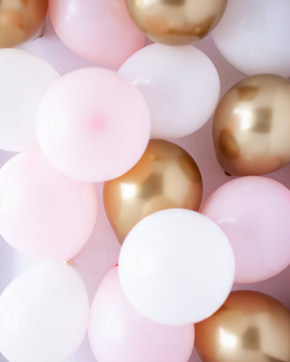 A mix of pink, white, and gold balloons arranged together, creating a festive and cheerful atmosphere.