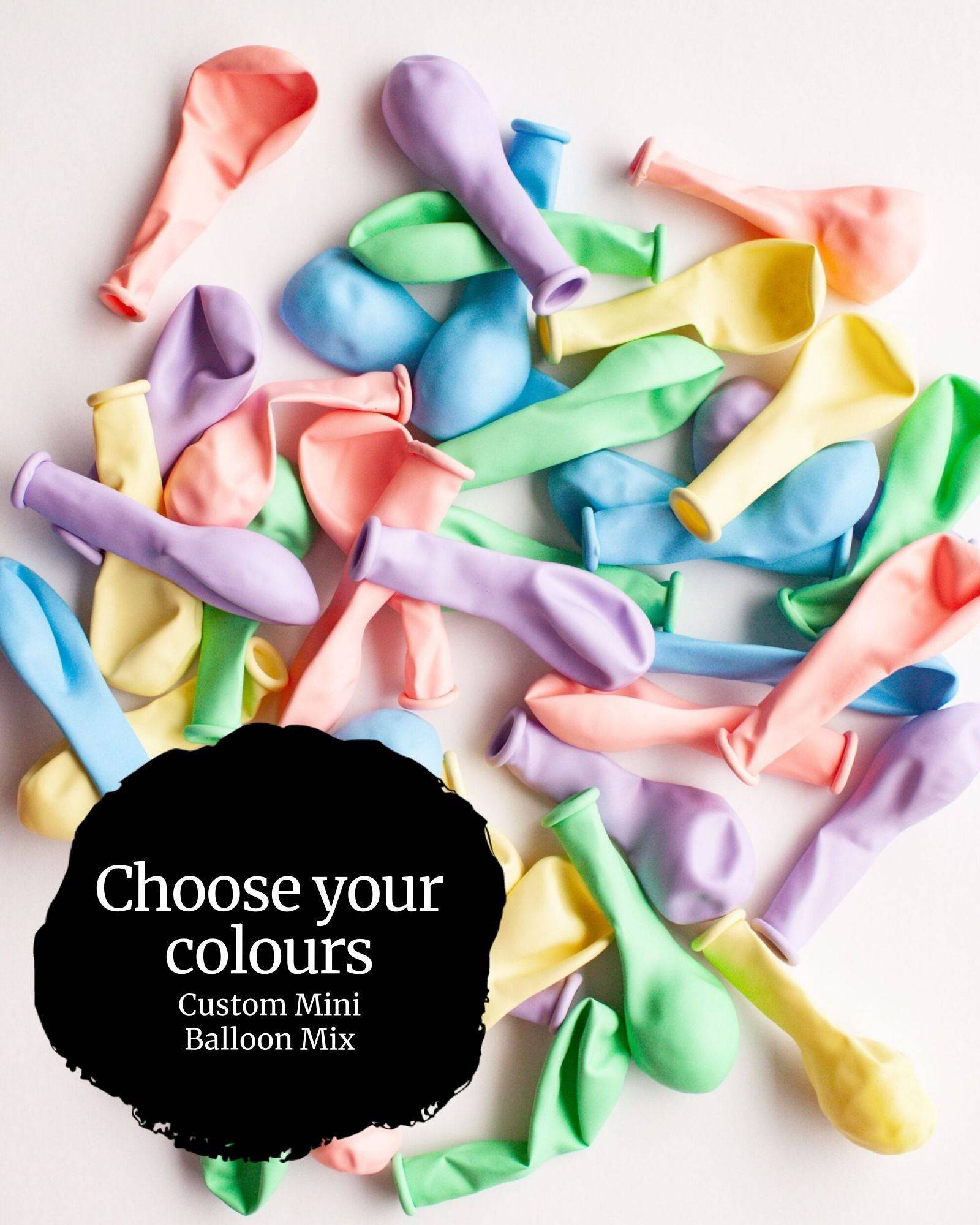 A colorful assortment of mini balloons in pastel shades scattered on a light background, inviting color selection.