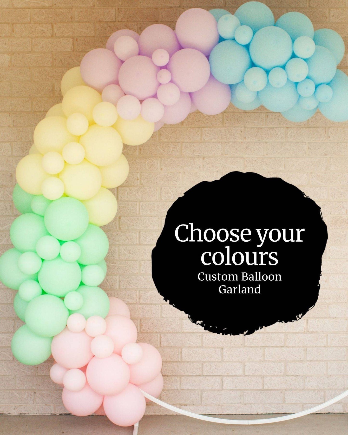 Colorful balloon garland in pastel shades, forming an arch against a light brick wall with a text overlay.