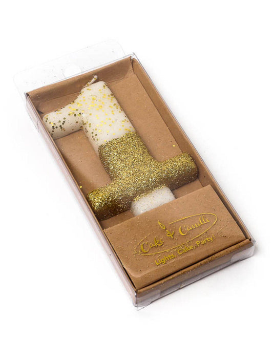 Gold glitter-dipped candle shaped like the number one, nestled in a clear box with a beige base.