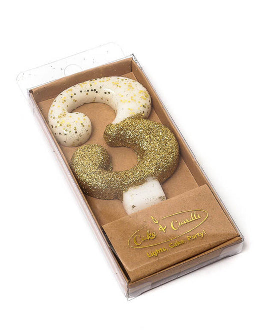 Gold glitter-dipped number three candle with a white base, packaged in a clear box with a brown insert.