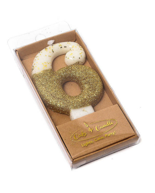 Gold glitter-dipped number six candle in a clear packaging with a brown base, adding festive sparkle to celebrations.