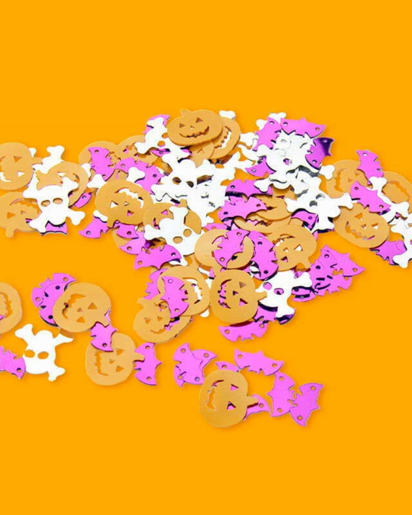 Colorful Halloween confetti featuring pumpkins, bats, and skulls, scattered on a vibrant orange background.