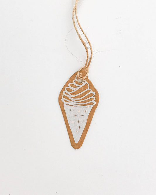 A brown tag shaped like an ice cream cone with white swirls and dots, suspended by a natural twine string.