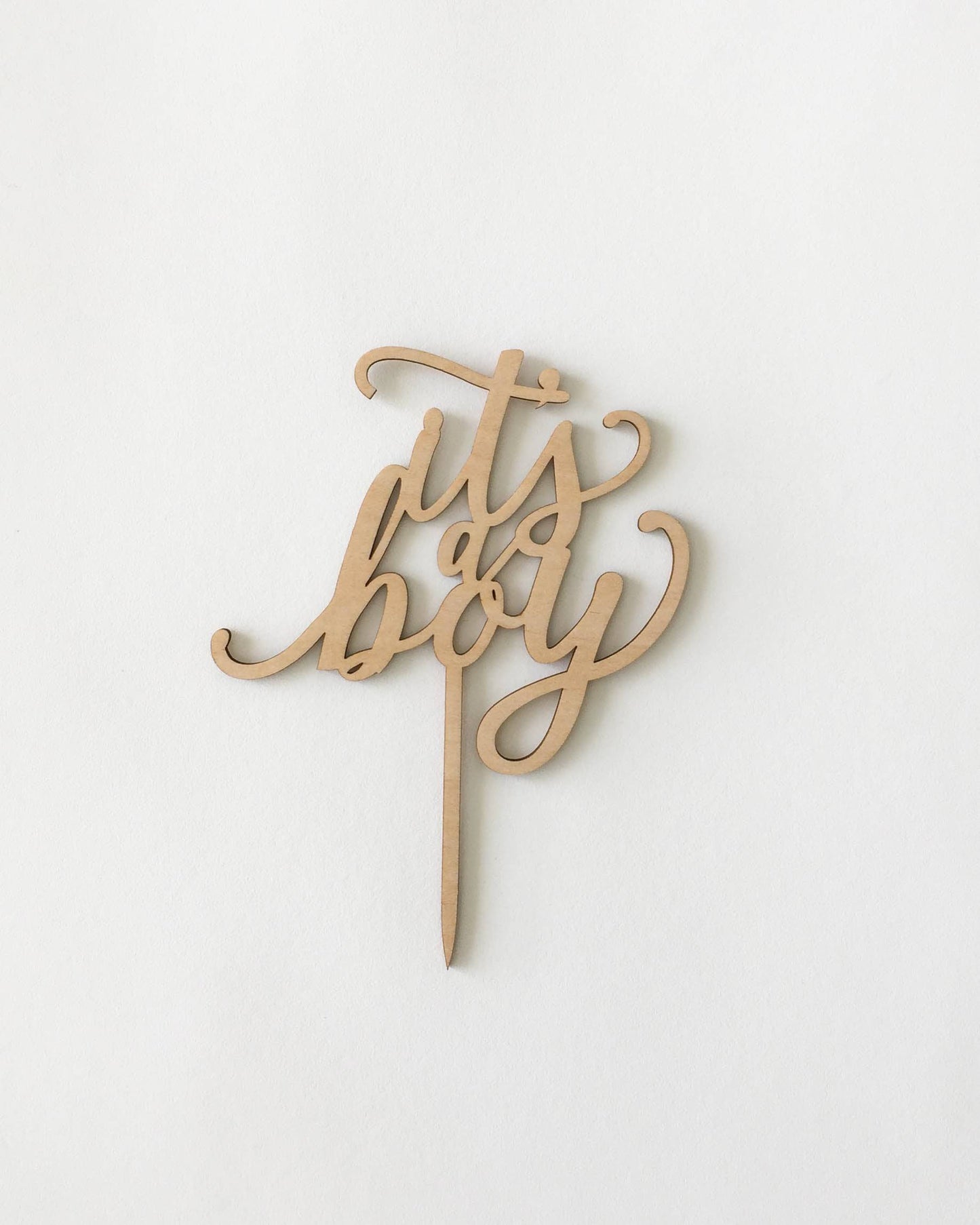 A wooden cake topper with elegant cursive text reading "It's a Boy" against a light background.