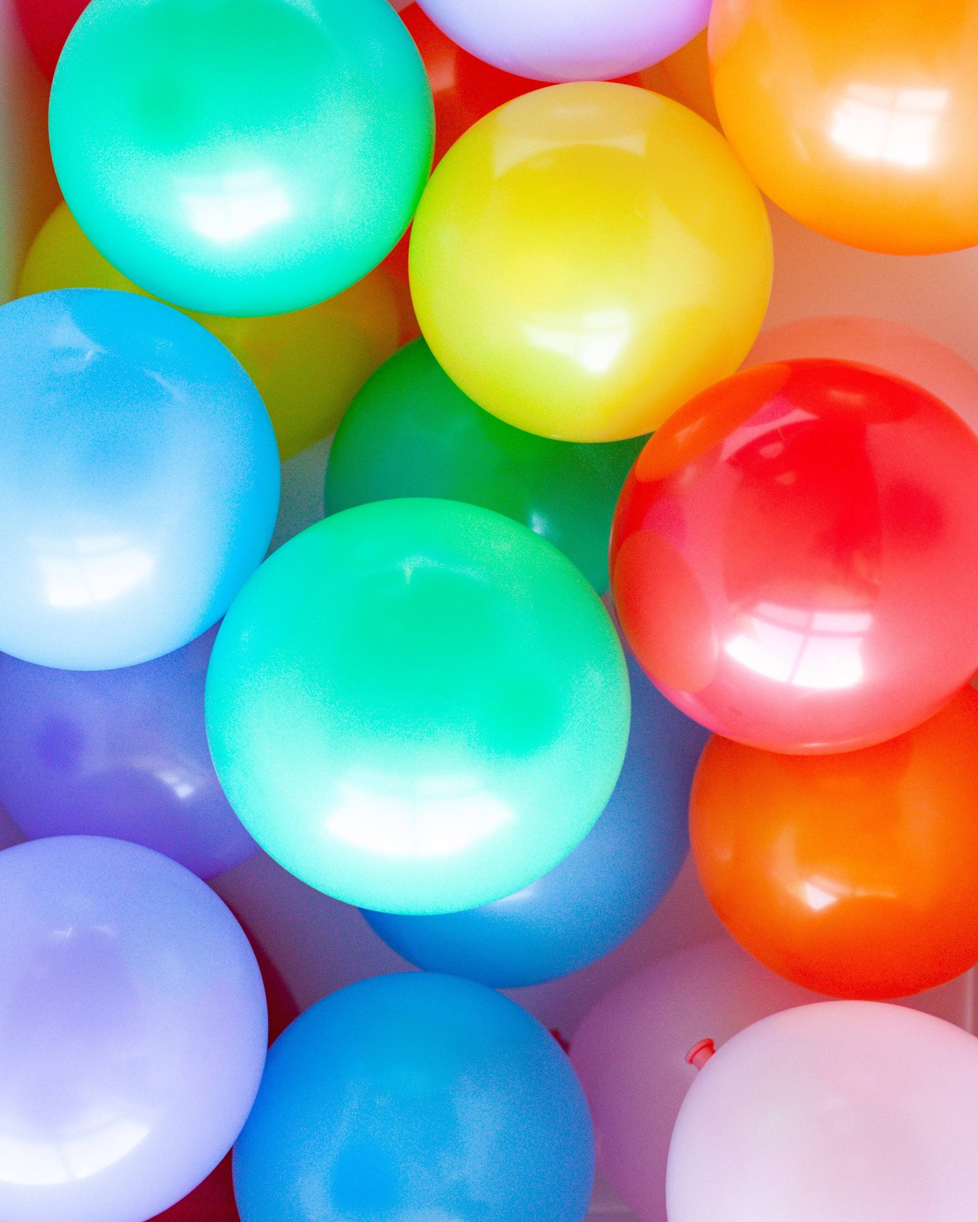 A vibrant assortment of glossy balloons in various colors, including red, green, yellow, and blue, closely packed together.