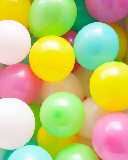 A vibrant mix of pastel balloons in various colors, including pink, yellow, green, and blue, clustered together.
