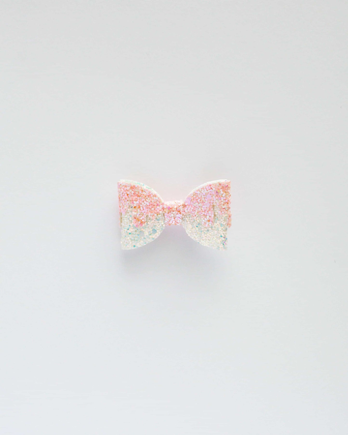 A sparkling pastel bow with glitter, set against a clean white background, radiating a playful and whimsical vibe.