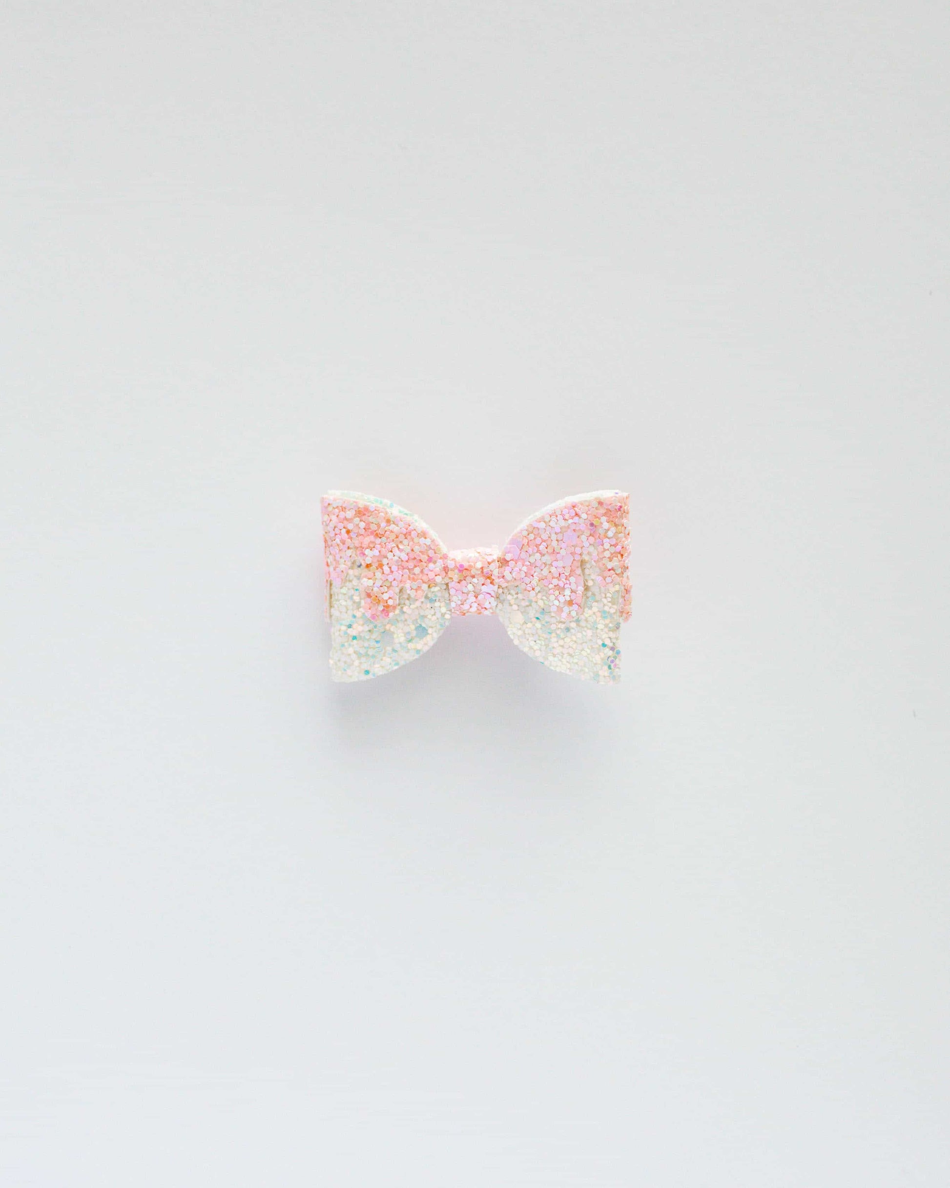 A sparkling pastel bow with glitter, set against a clean white background, radiating a playful and whimsical vibe.