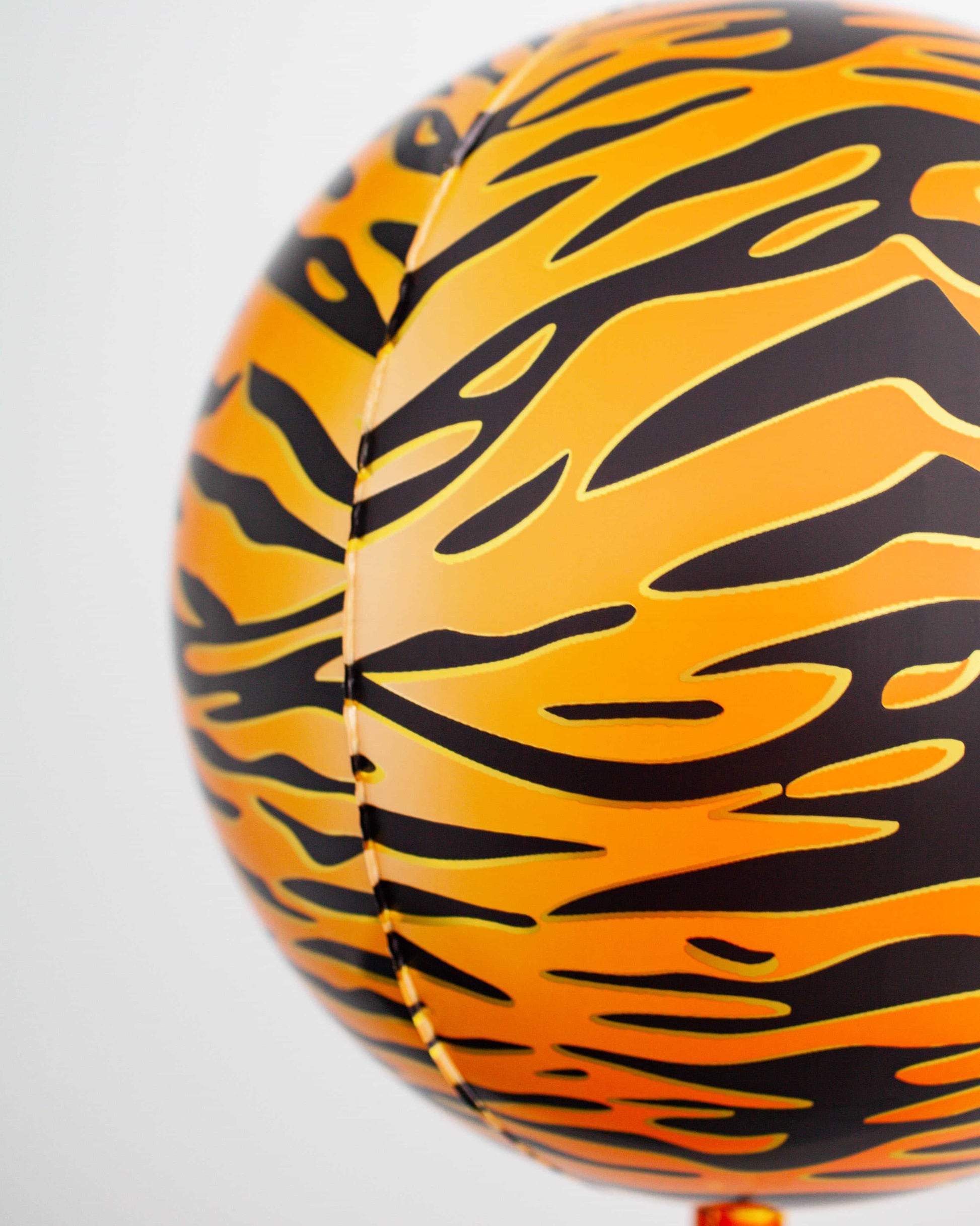 An orange sphere with black tiger stripes, featuring a glossy finish and vibrant colors against a white background.