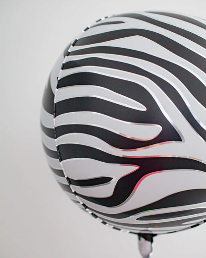 A black and white striped sphere with a glossy finish, suspended against a light backdrop.