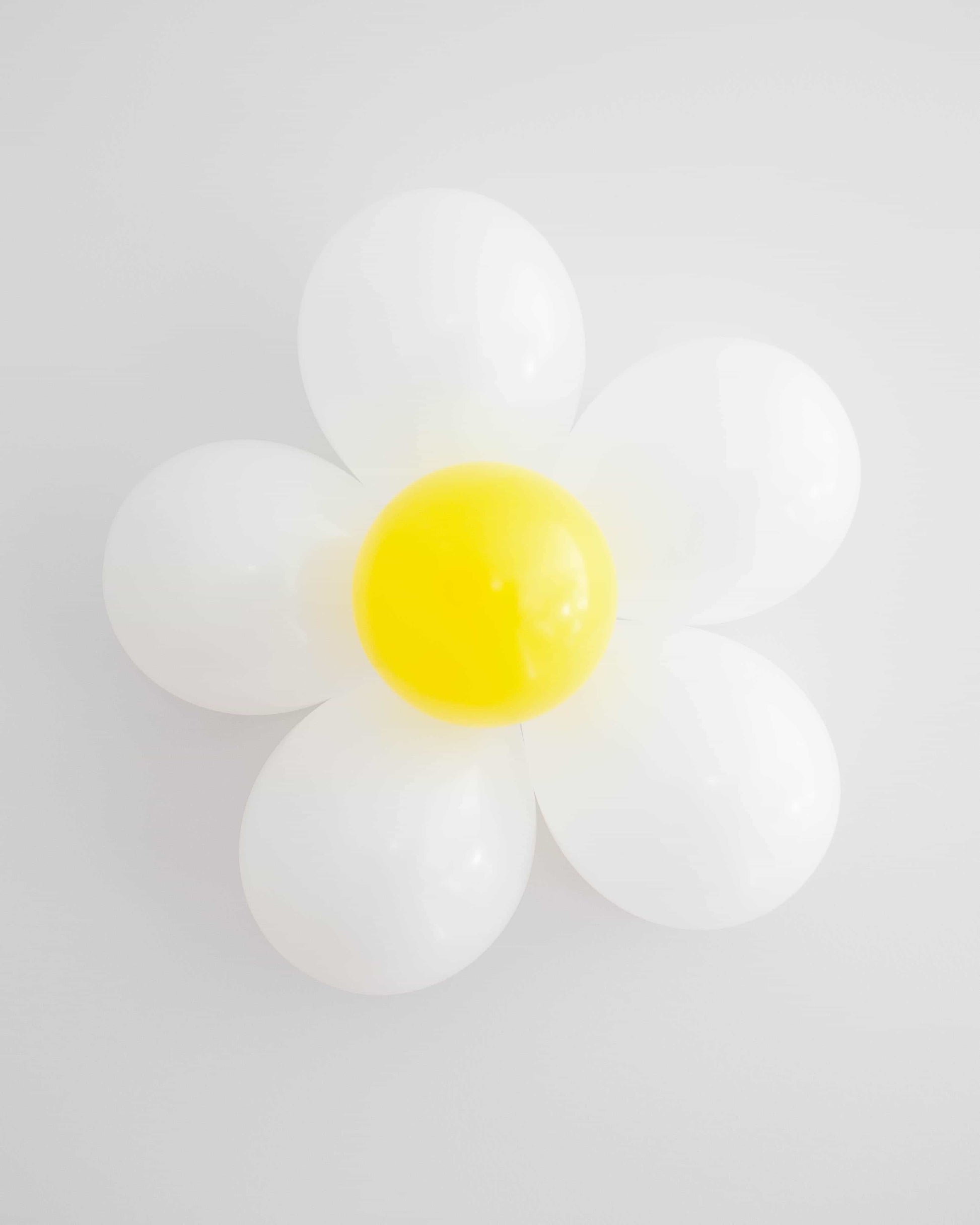 A whimsical arrangement of white and yellow round shapes resembling a daisy against a light background.