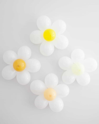 Four colorful flower shapes with white petals and bright centers arranged on a light background.