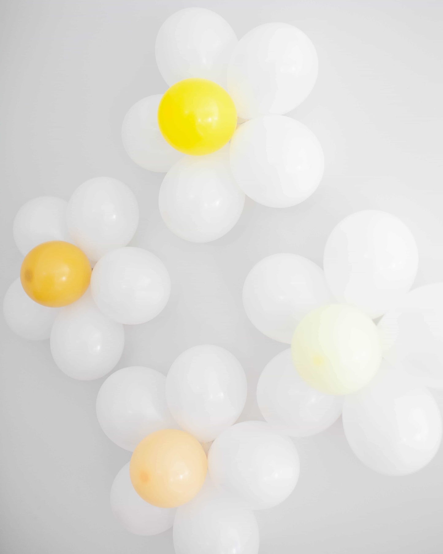 Three flower-shaped arrangements in white, yellow, and pale orange against a light background.