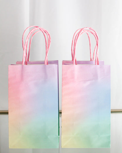 Two pastel gradient bags with twisted pink handles, displaying a soft blend of pink, blue, and green hues.