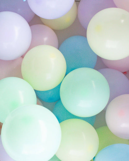 A colorful assortment of pastel balloons in soft hues of pink, green, and blue, clustered together playfully.