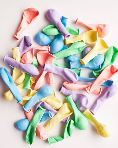 A colorful assortment of mini balloons in pastel shades scattered on a light background.