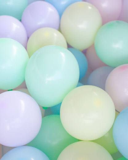 A vibrant mix of pastel balloons in soft shades of blue, green, and lavender, creating a cheerful, festive atmosphere.