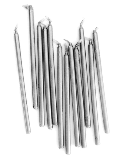 A collection of tall, silver candles arranged haphazardly, featuring tapered tops and slightly irregular shapes.