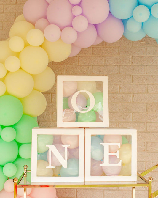 Three transparent boxes display pastel-colored balloons, arranged playfully against a vibrant balloon backdrop.