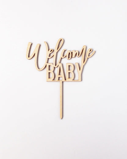 Wooden topper with elegant script reading "Welcome Baby" on a plain white background.